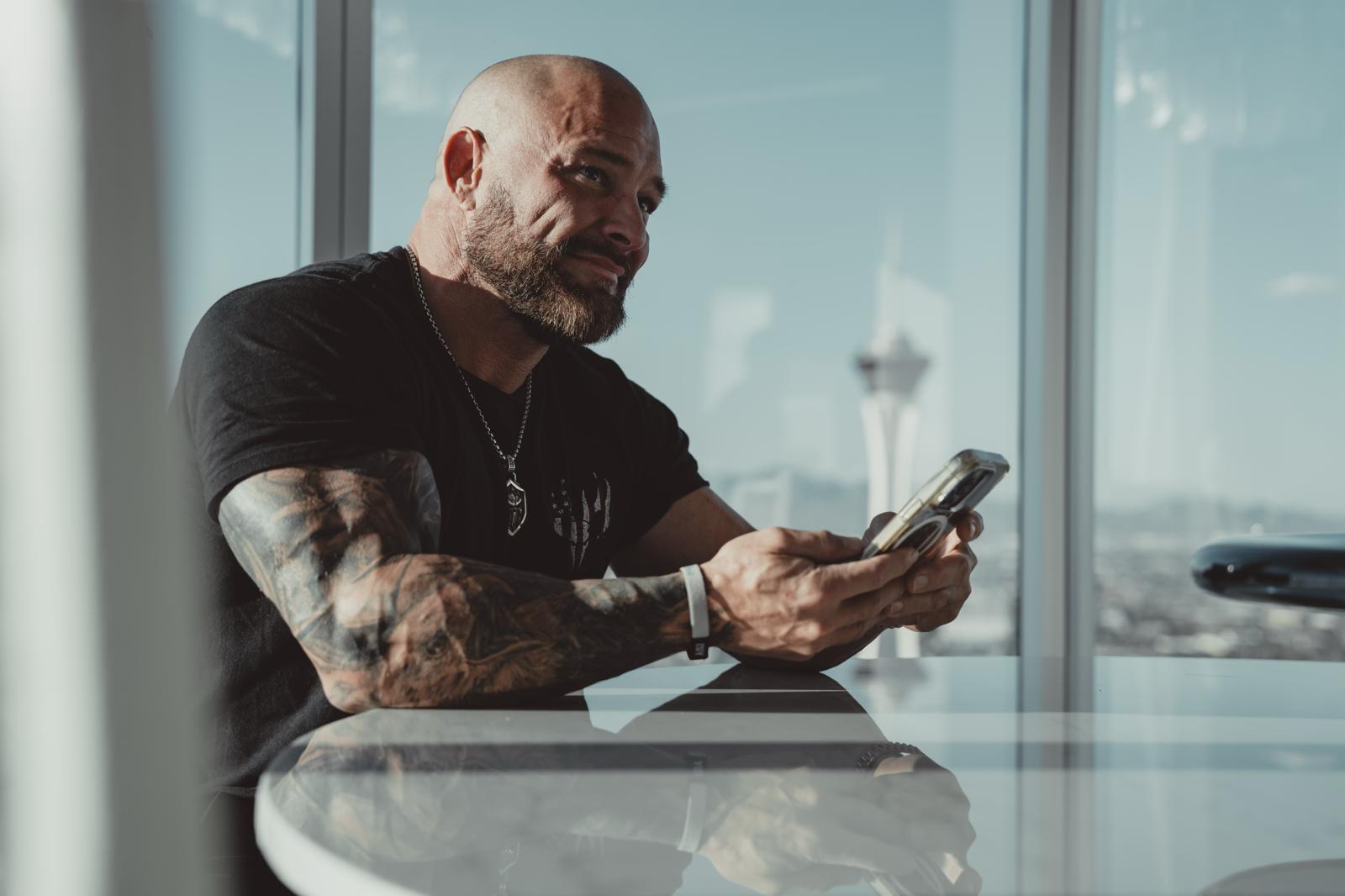 Joshua Denne reviewing his phone by a high-rise window